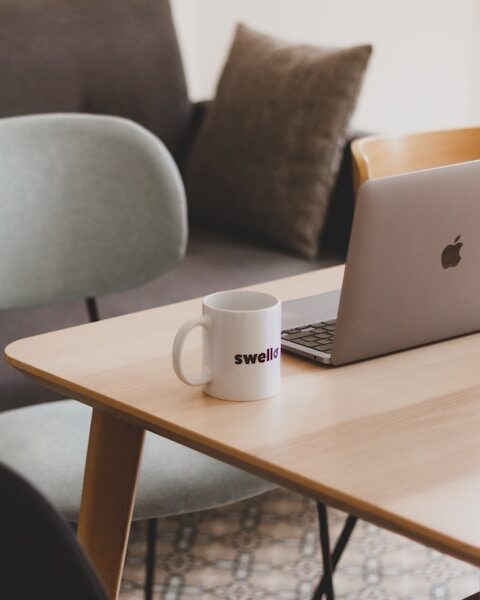 a coffee mug sitting on a table next to a laptop