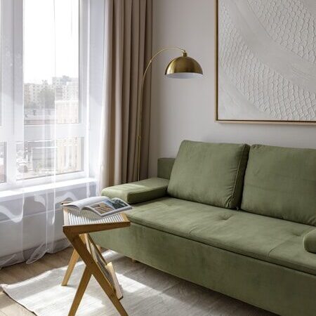 Modern living room with green sofa, large window, and lamp